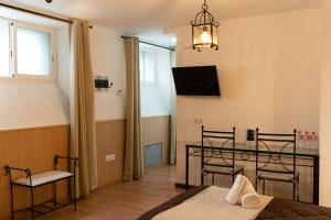 a room with a table and chairs and a television at Hotel Alquimia Cadiz in Cádiz