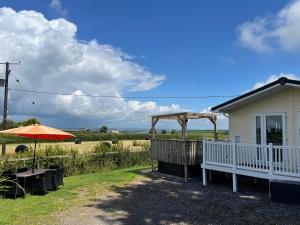 a house with a porch and an umbrella and a field at Mountain View Lodge in Whitland