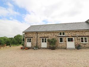 a stone cottage with white doors and a gravel yard at Graig Fawr in Builth Wells