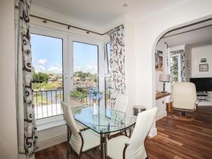 a dining room with a glass table and chairs and a window at Harbour View in Abersoch