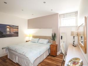 a white bedroom with a bed and a table at Harbour View in Abersoch
