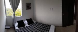 - une chambre avec un lit doté d'oreillers noirs et une fenêtre dans l'établissement Espectaculares Apartamentos con Piscina, à Montenegro