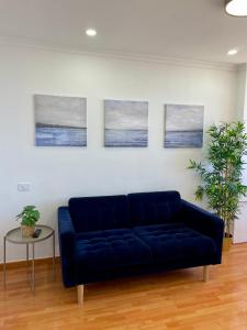 un divano blu in soggiorno con tre dipinti di Las Canteras View Home a Las Palmas de Gran Canaria