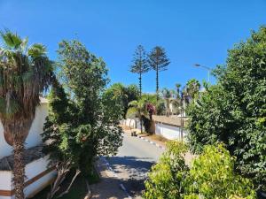 Blick auf eine Straße mit Bäumen und einem Zaun in der Unterkunft Appartement à 2 minutes de la plage Skhirat in Skhirat