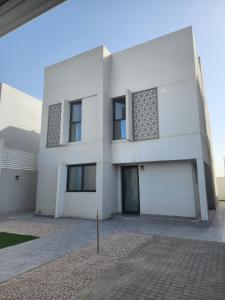 Uma casa branca com uma entrada à frente. em Nesaj Villa em Dammam