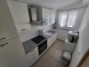 eine weiße Küche mit einer Spüle und einem Kühlschrank in der Unterkunft Apartment Maria in Ljubač