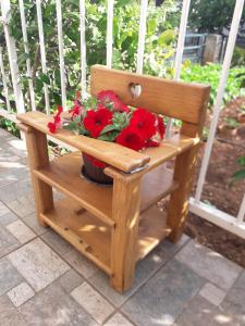 eine Holzbank mit einem Topf voller roter Blumen darauf in der Unterkunft Garden house Apartments in Vodice