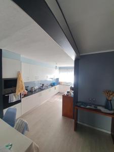a large kitchen with white cabinets and a blue wall at Enjoy the Island - Rua do Negrão in Ponta Delgada