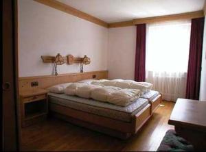 Schlafzimmer mit einem Bett und einem Fenster in der Unterkunft Residence Unterhuber in Innichen