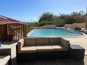 a couch sitting in front of a swimming pool at La Heliconia & Day Spa in Saint Georgeʼs