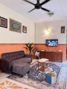 a living room with a couch and a flat screen tv at Perdana Cottage, Peaceful & Cozy Residential Area in Sungai Petani