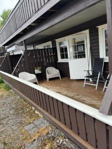 a porch of a house with two chairs and a table at Leilighet på Gautefall in Drangedal