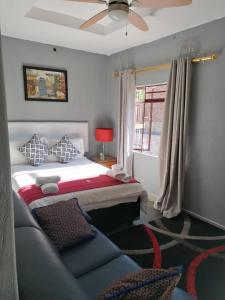 a bedroom with a bed and a couch and a window at dunduzu village lodge in Mzuzu