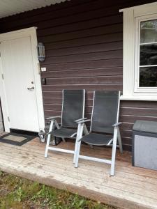 duas cadeiras sentadas no alpendre da frente de uma casa em Leilighet på Gautefall em Drangedal