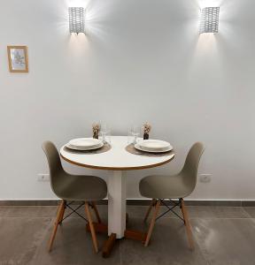 uma mesa branca com duas cadeiras e uma parede branca em Local 102 Apartment no Rio de Janeiro