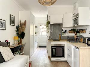 a kitchen with white cabinets and a living room at Le Cachot des Rois in Dourdan