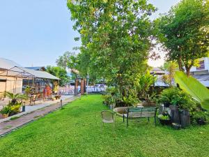a park with a bench and a table and chairs at Sherloft Home & Hostel in Chiang Mai