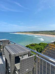 einen Balkon mit einem Tisch und Stühlen sowie einem Strand in der Unterkunft Golden Sands in Portrush