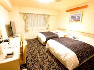 a hotel room with two beds and a television at APA Hotel Isehara-Ekimae in Isehara
