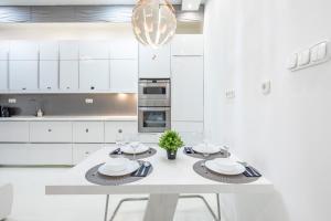 une cuisine avec des placards blancs et une table blanche avec des assiettes dans l'établissement Cozy & Central apartment with 2-bedroom, à Budapest