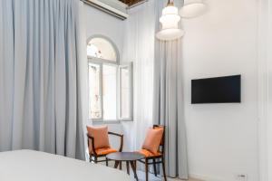 1 dormitorio con 2 sillas, 1 cama y 1 ventana en Palazzo Basilisco Luxury Suite, en Rovinj