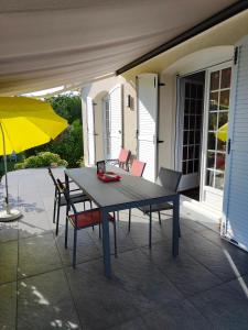 una mesa y sillas en un patio con sombrilla en A 15 mn ouest Caen, en Noyers-Bocage