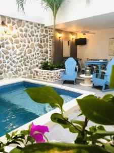 a pool with two blue chairs and a table at Hotel ADAZ Mediterráneo in Santa Marta