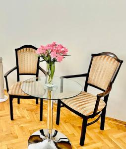 duas cadeiras e uma mesa de vidro com um vaso de flores em City Rooms em Budapeste