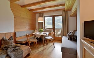 ein Wohnzimmer mit einem Tisch, Stühlen und einem TV in der Unterkunft Haus Sunnbichl in Hippach