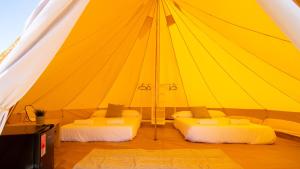 2 camas en una gran tienda amarilla en Glamping Atlántico, en Ferrol