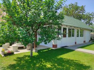 a small white building with a tree in a yard at Balogh Vendégház in Sárospatak