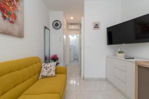 een woonkamer met een gele bank en een tv bij Apartment Leo in Trogir
