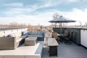 a patio with a couch and a table and an umbrella at Contemporary Zen Townhome with a View - Wash Park in Denver