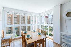 a dining room with a table and chairs and windows at Apartamento Costa de Marfil Touriplaya a 200 metros del mar SOLO FAMILIAS in Playa de Gandia