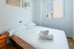 a bedroom with a white bed with towels on it at Apartamento Costa de Marfil Touriplaya a 200 metros del mar SOLO FAMILIAS in Playa de Gandia