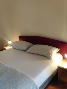 een bed met 2 kussens en een rood hoofdeinde bij Apartments F&T in Mošćenička Draga