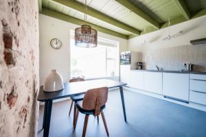 a kitchen with a table and chairs and a clock at Dyk hûs in Moddergat