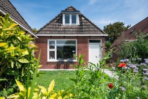 a brick house with a white door and a window at Dyk hûs in Moddergat +11 photos