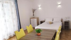 a bedroom with a bed and a table with yellow chairs at Active Apartments Koper in Koper