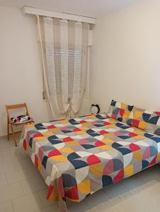 um quarto com uma cama colorida e uma janela em Seafront em San Sostene Marina