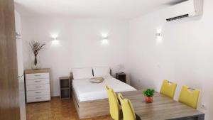 a bedroom with a bed and a wooden table with yellow chairs at Active Apartments Koper in Koper