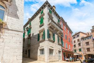 Un edificio con ventanas verdes en una ciudad. en Palazzo Basilisco Luxury Suite, en Rovinj