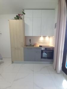 a kitchen with white cabinets and a sink and a stove at Room and terrace in Krk