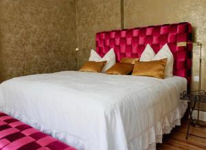 a large white bed with a pink head board at Gutshaus Gevezin in Gevezin