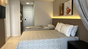 a small bedroom with a bed with white pillows at Resort Ecoar in Gaspar