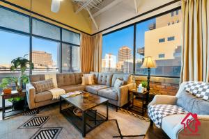 a living room with couches and a large window at Elevated Route 66 ABQ Penthouse- An Irvie Home in Albuquerque