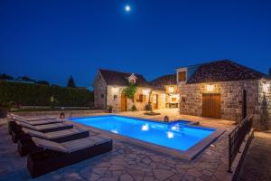 a swimming pool in the backyard of a house at night at VIP Luxury villa with a heated pool and jacuzzi-Granny's Gold in Lovreć
