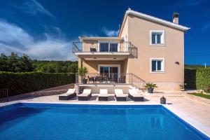 a villa with a swimming pool in front of a house at VIP Luxury villa with a heated pool and jacuzzi-Granny's Gold in Lovreć
