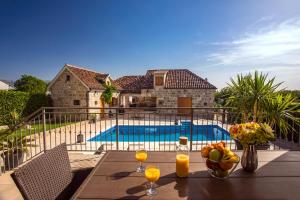 a table with a bowl of fruit and drinks on a balcony with a pool at VIP Luxury villa with a heated pool and jacuzzi-Granny's Gold in Lovreć