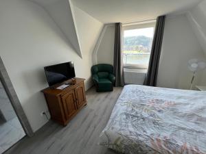 a bedroom with a bed and a television and a chair at Riverbank Guest House in Namur